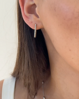 Close-up of an ear wearing a silver hoop earring with a blurred background