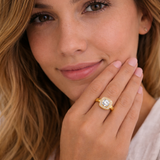 Woman wearing a gold ring with a diamond, close-up of hand and face.