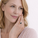 Woman wearing a ring with a black gemstone on a white background
