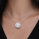Silver necklace with a round halo crystal pendant worn by a person against a dark background