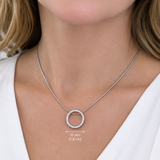 A close-up of a woman wearing a delicate silver chain necklace with a small, round, diamond-pierced pendant. A white text overlay indicates the pendant's diameter is 15 mm (0.