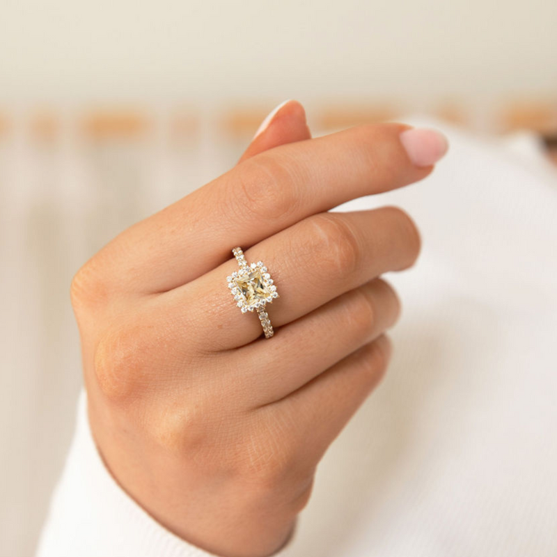 Hand wearing a diamond ring with a blurred background