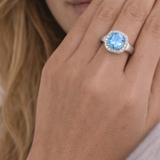 Close-up of a hand wearing a ring with a blue gemstone.